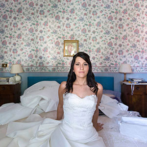 ritratto fotografico sposa attende di uscire di casa e siede sul letto