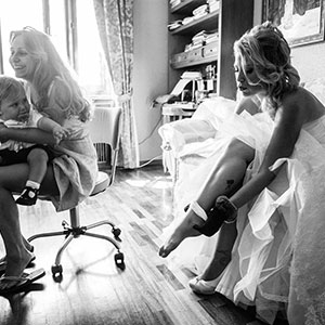 reportage fotografico di nozze, backstage della preparazione: immagine di sposa con bimbo mentre si infila le calze
