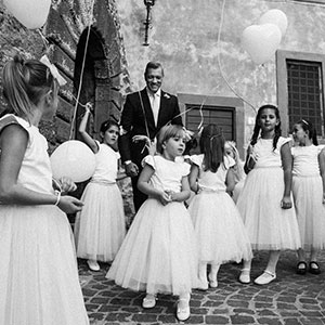 immagine di damigelle con palloncini bianchi intorno allo sposo nelle vie di Bracciano, Roma