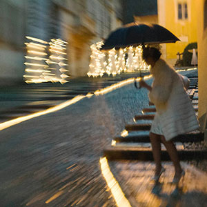fotogiornalismo di matrimoni: matrimonio invernale la sposa con ombrello sulla salita della Motta con lo sfondo della chiesa d’ Orta in Piemonte